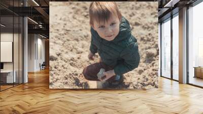 A little boy is climbing a sand mountain. Wall mural