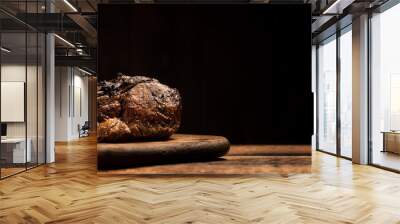 A whole piece of baked meat on a wooden board on a black background. Banner. Place for your text. Wall mural