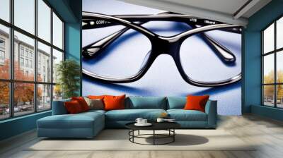 Close-Up of Modern Simple Eyeglass Frame on Smooth Blue Surface - Functional Design for Optical and Fashion Use Wall mural