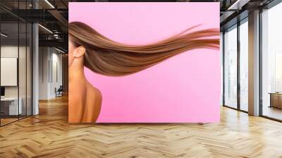 Smiling woman with long flowing hair against pink background Wall mural