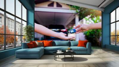 male hand holding a remote car key and handing it over to give another person Wall mural