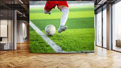 Selective focus to soccer ball with blurry soccer player run to shoot it. Wall mural