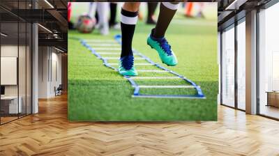 Soccer player jogging and jump between marker for football training with blurry other players waiting to follow him. Wall mural