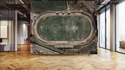 Old abandoned football stadium. Remains of a green lawn. Shabby abandoned stadium. Wall mural