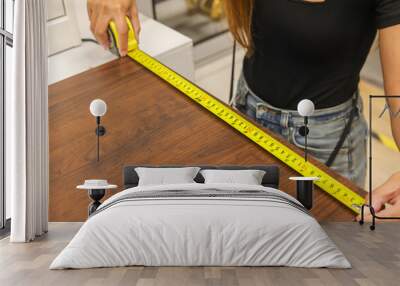 Image of the measuring process of the table with a measuring tape. Measuring roulette. Construction concept Wall mural