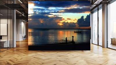 A bright and colorful panorama of sunset on the ocean in Bagamoyo. Silhouette of people and local boats. Wall mural