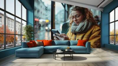 A woman is sitting on a bus and looking at her cell phone Wall mural