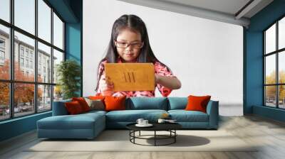 Asian child or kid girl smile wearing blue block glasses to learn from home or study online on computer tablet and communication or people play game on street footpath and dirty white wall with space Wall mural