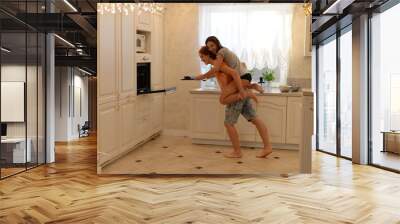 loving couple preparing food in the kitchen having fun Wall mural