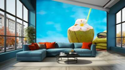 coconut with a straw on the edge of a deckchair against a blue water pool background Wall mural