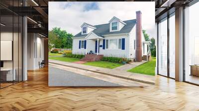 Cute brightly painted white shingled cottage with blue shutters. coastal town on cloudy day. Wall mural