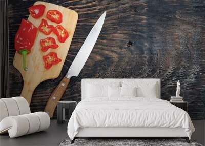 Fresh raw sweet pepper (bell pepper) on a cutting board with a knife. Chopped pepper pieces are ready to cook. Dark wooden table, top view. Wall mural