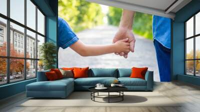 a hands of happy parent and child on nature on the road in park background Wall mural