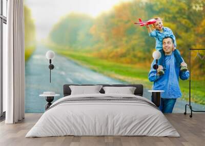 A Happy parent walks along the road with a child and an airplane in the park on nature travel Wall mural