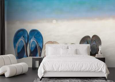 A Slippers of the whole family in the sand by the sea on nature while traveling. Rest by the water on vacation with shoes. Wall mural