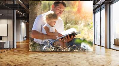 Happy parents with a child read the Bible in the nature park Wall mural