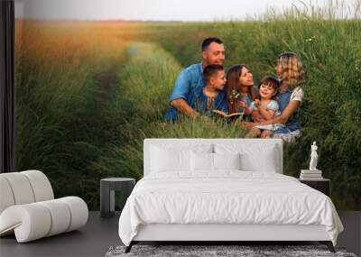 young family with children reading the Bible in nature Wall mural