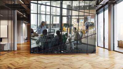 Business meeting. Group of happy smiling multiracial business people discussing project, working together while sitting in a conference room in the modern coworking space Wall mural