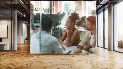 Business meeting. Mature businessman discussing something with his young colleagues while sitting together at the office table in the modern office Wall mural