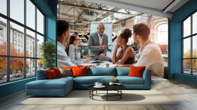 Business meeting. Mature businessman explaining something to his colleagues while sitting at the office table in modern offic Wall mural