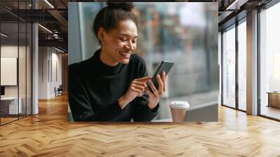 Cheerful woman holding phone during working in cafe near window. Distance work concept Wall mural