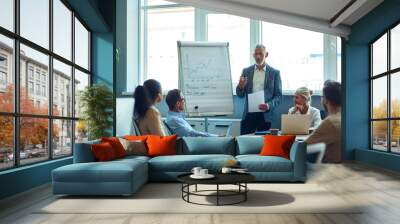 Confident mature businessman giving a presentation, explaining something to colleagues while having a meeting in the office Wall mural