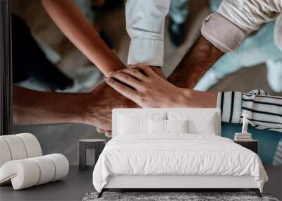 Cooperation. Top view of people holding hands together while standing in the office Wall mural