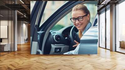 Great day. Beautiful and happy middle aged business woman in classic wear getting out of her modern car, she is arrived at work in the morning Wall mural