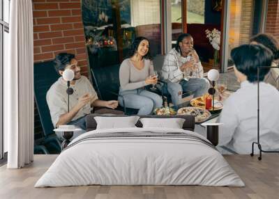 Group of friends enjoying in conversation and drinking wine during holiday party at home terrace Wall mural