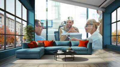 Group of multiracial business people sitting in board room in the modern office and discussing something while having a meeting Wall mural