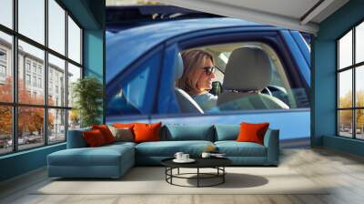 Happy attractive caucasian woman, business lady wearing eyeglasses driving her modern car and smiling Wall mural