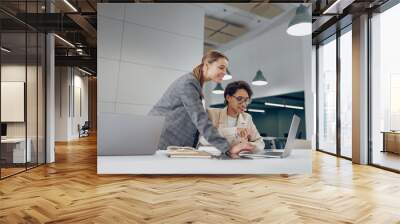 Happy business colleagues having discussion over laptop while working in stylish coworking Wall mural