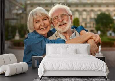 I love my husband. Portrait of cheerful senior couple in casual clothing embracing each other and looking at camera with smile while standing together outdoors Wall mural