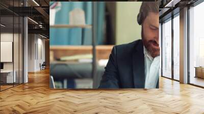 Male operator using headset and computer while talking with customers online on colleague background Wall mural