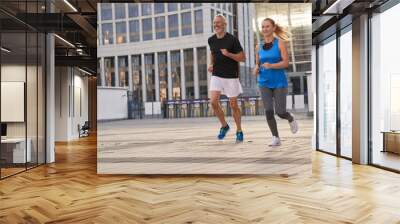 Mature couple, man and woman exercising and jogging together in the city on a warm summer day Wall mural