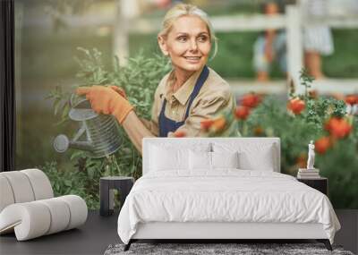 Middle aged caucasian female gardener watering plants Wall mural