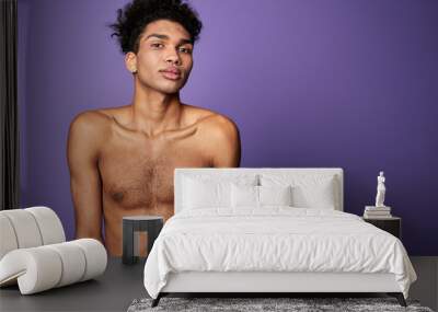 Portrait of latin american transgender model on purple background. Handsome young man posing camera Wall mural