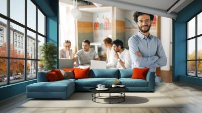 Portrait of smiling businessman standing in modern office on colleagues background Wall mural