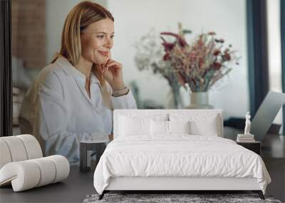 Smiling business woman working on laptop, making notes in cozy coworkign space interior Wall mural