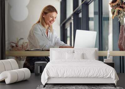 Smiling business woman working on laptop in cozy coworking space interior. Distance work concept Wall mural