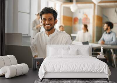 Smiling Businessman working laptop while sitting in modern office on colleagues background Wall mural