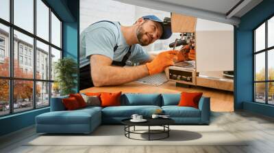 Smiling young man fixing coffee machine in cafe Wall mural