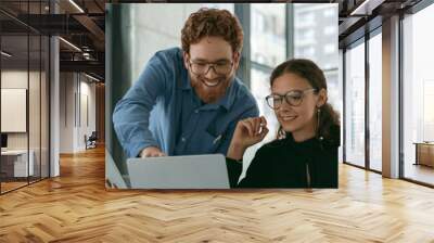 Two diverse business colleagues disscuss biz issue while use laptop in office background Wall mural