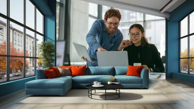 Two diverse business colleagues disscuss biz issue while use laptop in office background Wall mural