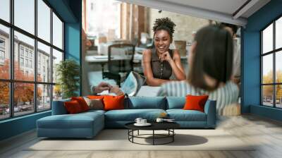 We are one team! Young and cheerful afro american woman smiling while having a meeting with colleagues in the modern office Wall mural