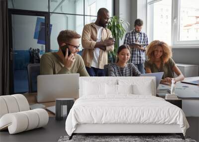 Working on project together. Group of multiracial coworkers communicating, talking, sharing fresh ideas while working in the modern coworking space Wall mural