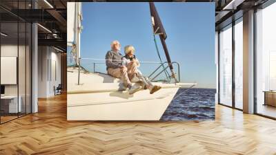 You, me and the sea. A happy senior couple sitting on the side of a sail boat on a calm blue sea enjoying view Wall mural