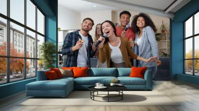 Young asian girl holding microphone and singing while playing karaoke with best friends at home. Group of people having fun together, drinking and eating pizza. Karaoke party Wall mural