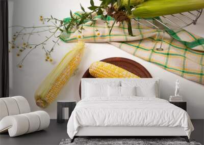 Clay plate with two cobs sweet corn on white wooden background.. Wall mural