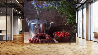 Delicious chocolate cake with sweet cherry, vintage kettle and bouquet of blue flowers on dark wooden background.. Wall mural